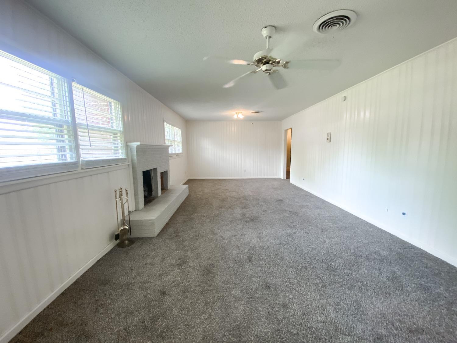 4010 47th Street Lubbock, TX 79413 - Photo 8 of 20 an empty room with a fireplace and windows