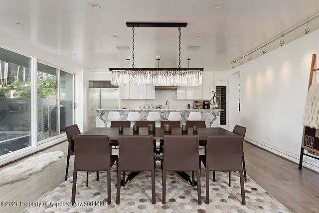 a kitchen with stainless steel appliances kitchen island granite countertop a sink a stove a refrigerator a dining table and chairs with wooden floor