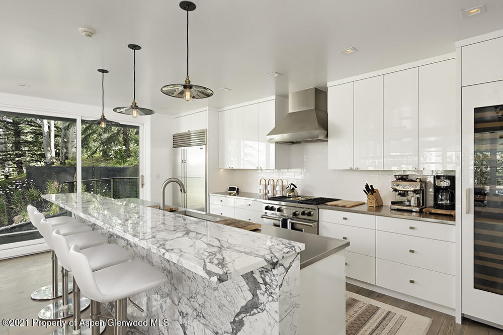 546 Edgewood Lane Snowmass Village, CO 81615 - Photo 8 of 60 a kitchen with stainless steel appliances kitchen island granite countertop a sink a stove a refrigerator a dining table and chairs with wooden floor