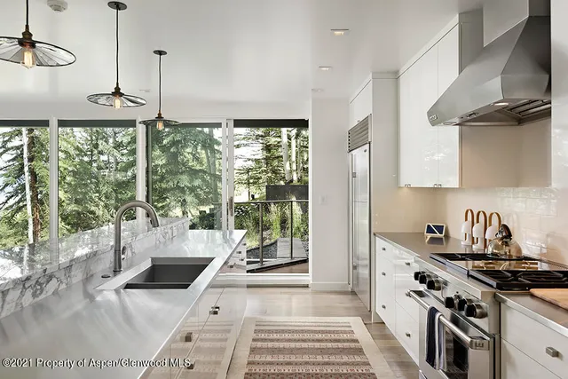 a kitchen with stainless steel appliances a sink a stove and a wooden floor