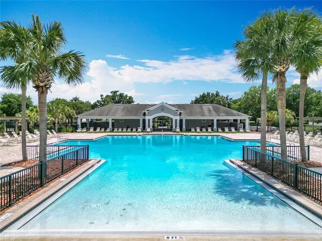 a view of a swimming pool with lawn chairs under an umbrella