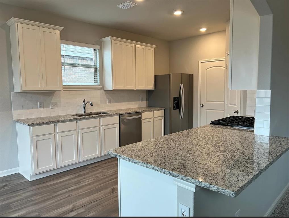 2013 Emma Court Anna, TX 75409 - Photo 3 of 20 Kitchen featuring white shaker-style cabinetry, a stainless steel sink with a gooseneck faucet, light-toned granite countertops, and wood-finish flooring