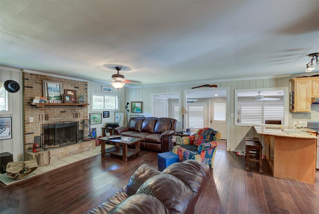 459 Dollie Moore Road Ringgold, LA 71068 - Photo 3 of 19 Brick fireplace with hearth, wood-finish flooring, ceiling fan, and shaker-style cabinetry