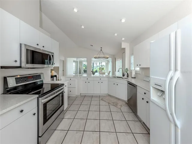 a large kitchen with a stove top oven a sink a counter space and cabinets