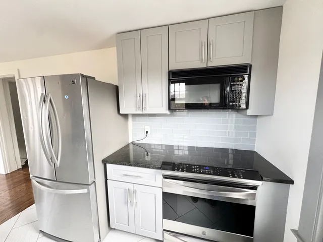 a kitchen with granite countertop white cabinets and stainless steel appliances