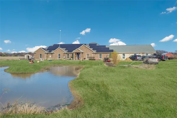 a view of a house with a yard and a pond