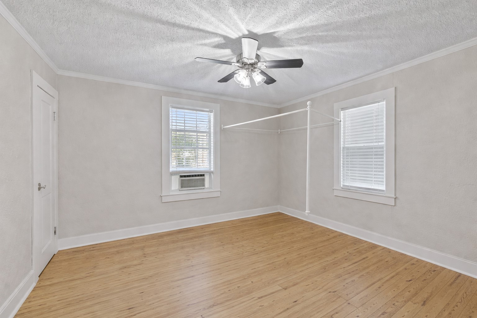 1202 East 29th Street, Unit A Austin, TX 78722 - Photo 15 of 22 Spare room featuring light wood-style floors, ceiling fan, crown molding, a textured ceiling, and cooling unit