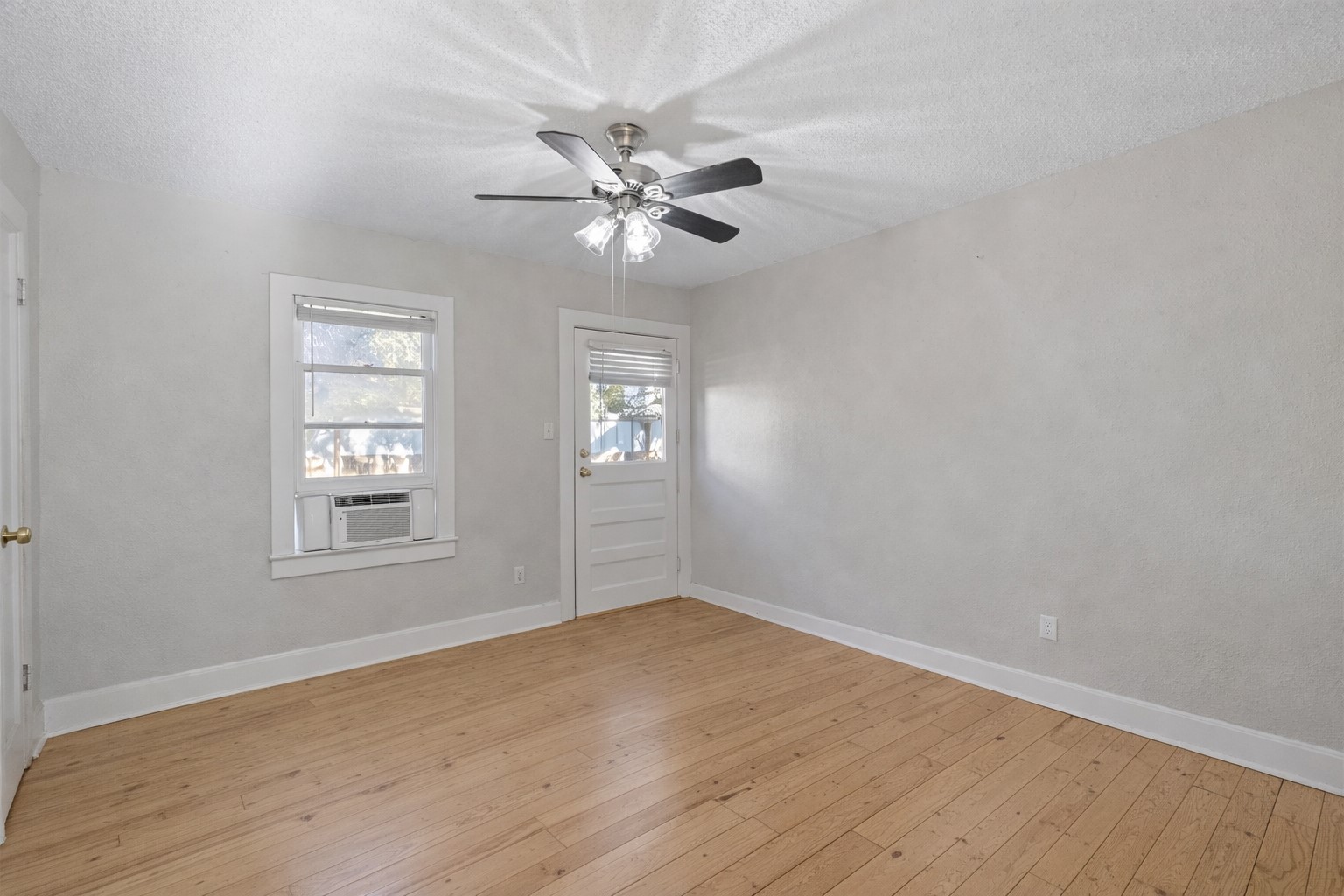 1202 East 29th Street, Unit A Austin, TX 78722 - Photo 17 of 22 Empty room with a textured ceiling, light wood-style floors, a ceiling fan, and cooling unit