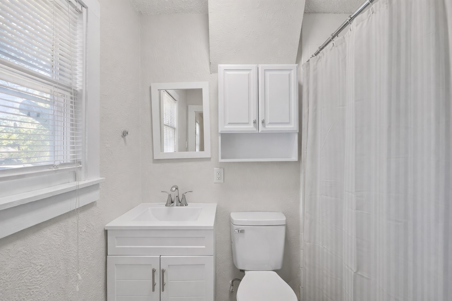 1202 East 29th Street, Unit A Austin, TX 78722 - Photo 19 of 22 Bathroom featuring a textured wall, vanity, and a shower with curtain