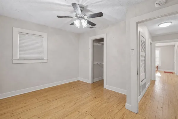 a view of empty room with wooden floor and fan