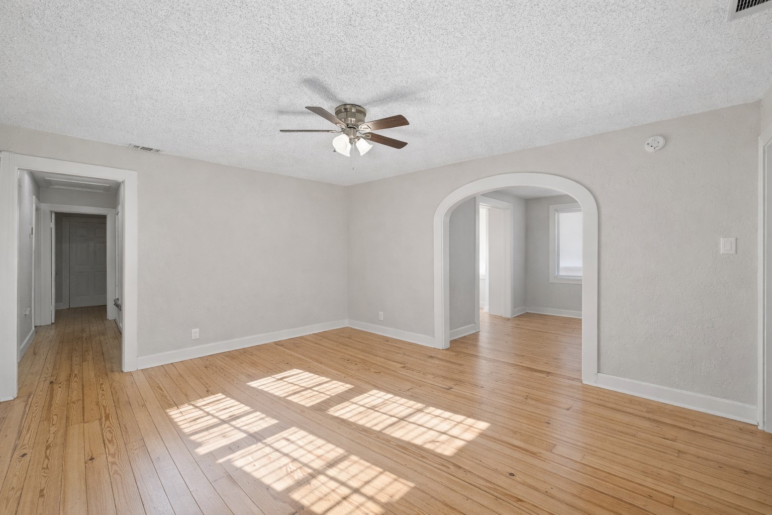 1202 East 29th Street, Unit A Austin, TX 78722 - Photo 8 of 22 Spare room featuring light wood finished floors, ceiling fan, arched walkways, and a textured ceiling