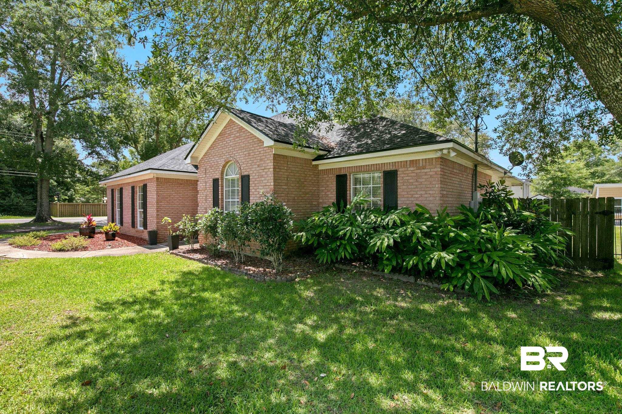 520 Juniper Place Drive Foley, AL 36535 - Photo 1 of 35 Brick exterior residence featuring a prominent arched window, black louvered shutters, and a dark shingle roof