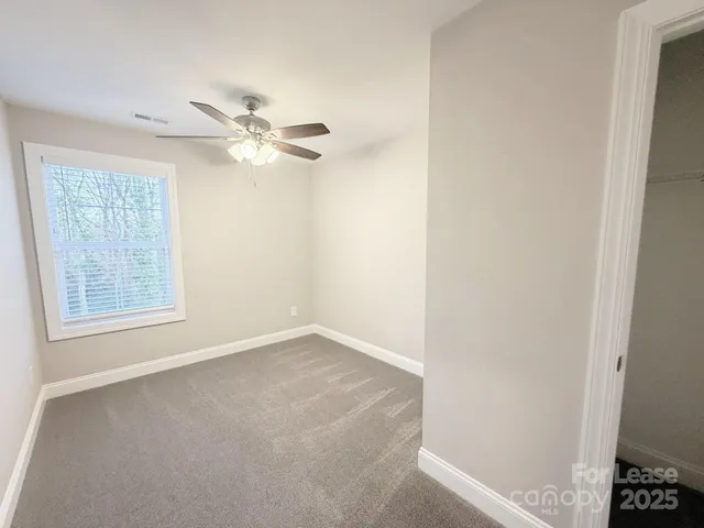 an empty room with a window and a fan