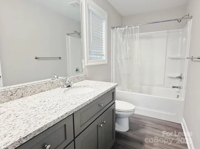 a bathroom with a granite countertop sink a toilet and shower
