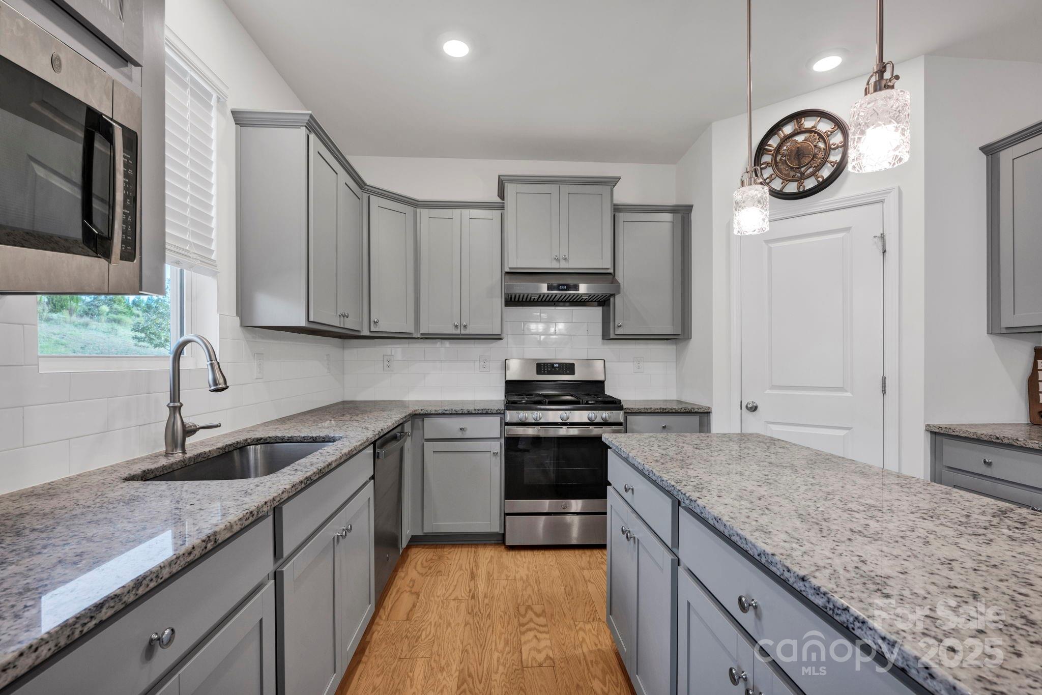 2712 Trinity Street Monroe, NC 28110 - Photo 7 of 48 a kitchen with stainless steel appliances granite countertop a sink a stove and a microwave oven with white cabinets