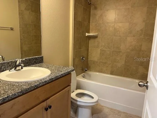 a bathroom with a granite countertop sink a toilet and bathtub