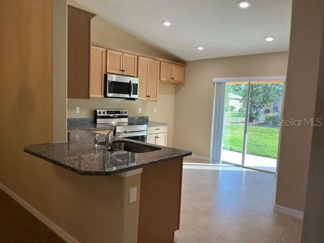 a kitchen with kitchen island granite countertop a sink and a stove top oven