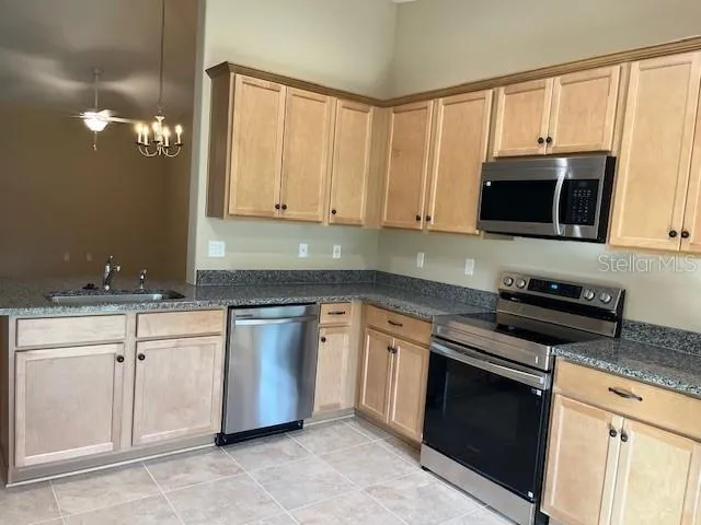 a kitchen with granite countertop white cabinets and stainless steel appliances
