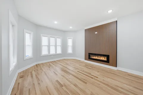 an empty room with wooden floor a fireplace and windows