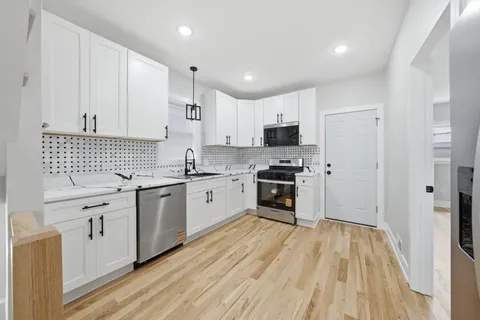 a kitchen with granite countertop white cabinets sink and stainless steel appliances