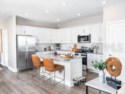 4519 Trinity Way, Unit THC1 Kissimmee, FL 34746 - Photo 5 of 14 a kitchen with a sink a stove a refrigerator cabinets and a dining table