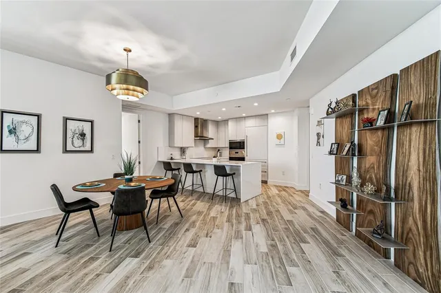 a kitchen with a stove a refrigerator and a dining table with wooden floor