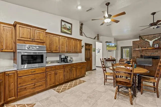 a kitchen with stainless steel appliances kitchen island granite countertop a table chairs in it and wooden floors
