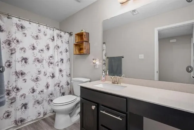 a bathroom with a granite countertop sink a toilet and shower