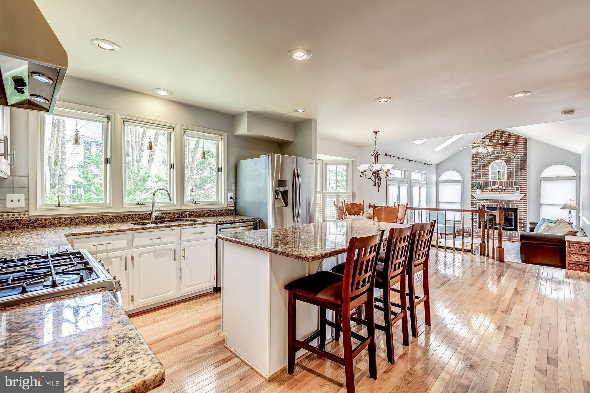 6402 Springhouse Circle Clifton, VA 20124 - Photo 23 of 43 a kitchen with stainless steel appliances granite countertop a stove a refrigerator a dining table and chairs with wooden floor