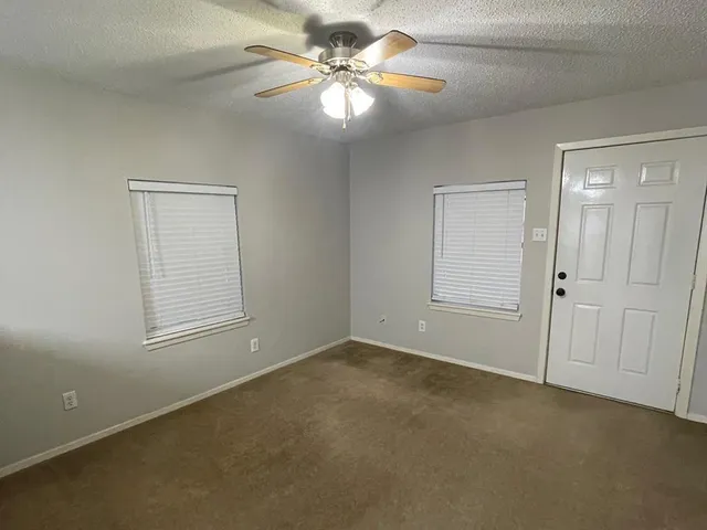 an empty room with windows and fan