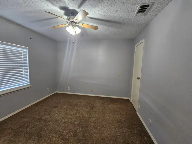 an empty room with a window and a fan