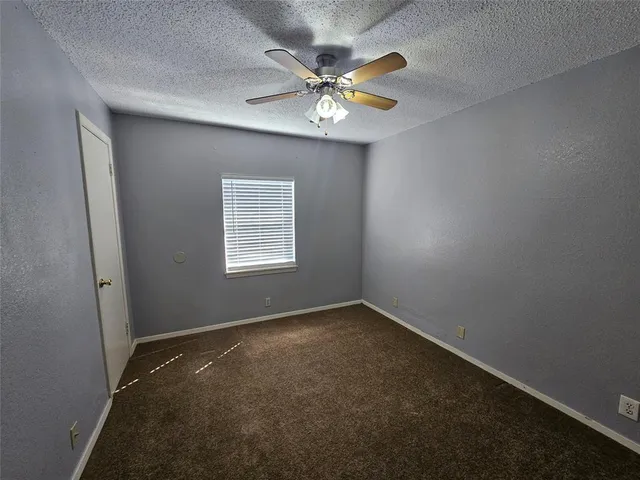 an empty room with a chandelier fan and windows