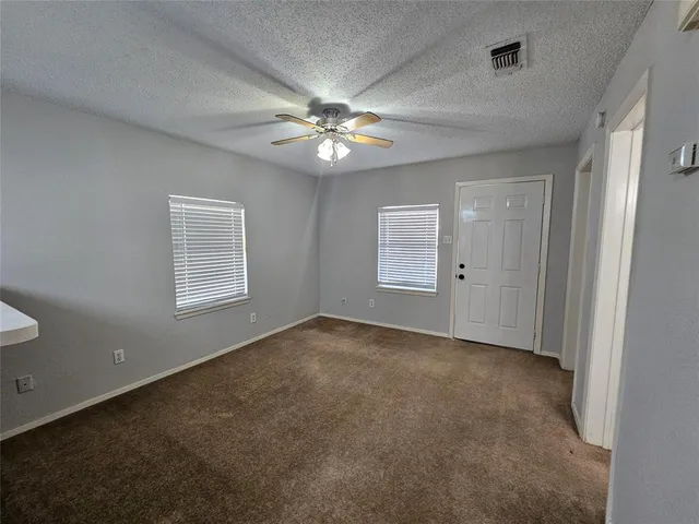 an empty room with windows and fan
