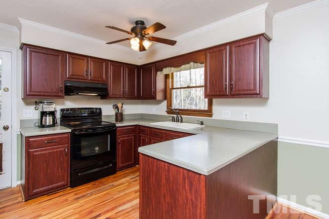 1100 Toppe Ridge Court Raleigh, NC 27615 - Photo 6 of 22 a kitchen with granite countertop wooden cabinets a stove a sink and a potted plant