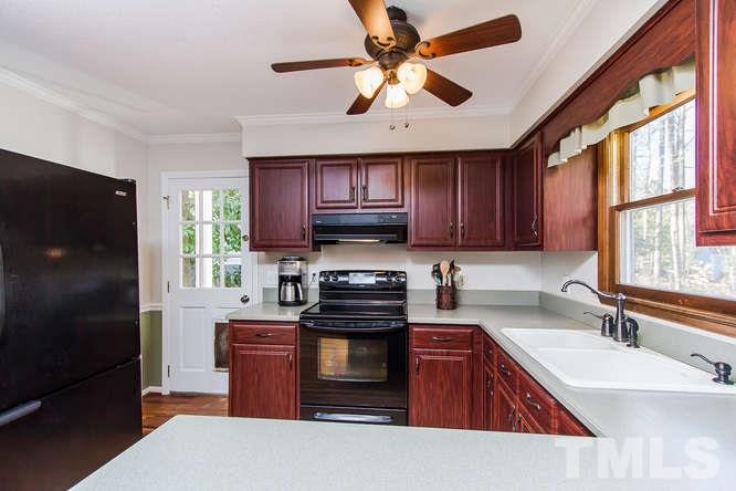 1100 Toppe Ridge Court Raleigh, NC 27615 - Photo 9 of 22 a kitchen with a refrigerator a sink and wooden cabinets