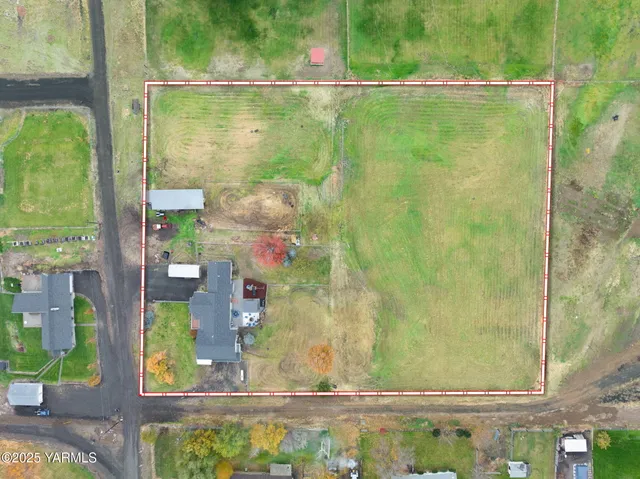 a aerial view of a house next to a big yard and large trees