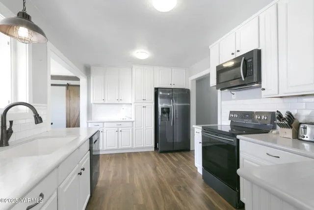 a kitchen with a sink white cabinets and stainless steel appliances