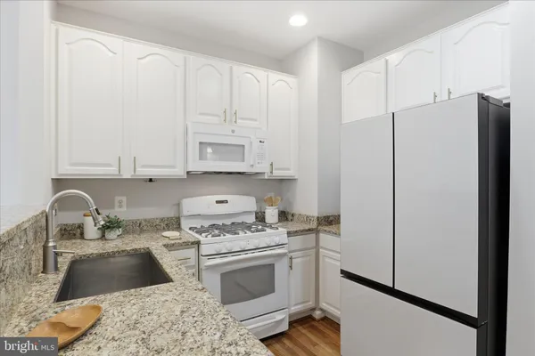 a kitchen with granite countertop white cabinets and white appliances