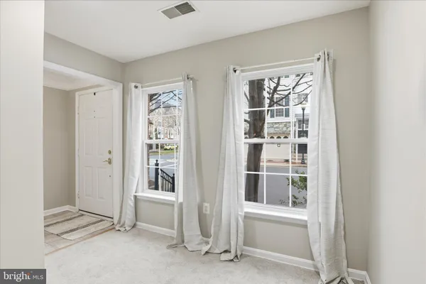 a view of an empty room with wooden floor fireplace and a window