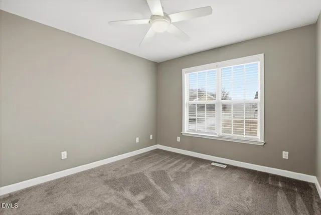 an empty room with a chandelier fan and wooden floor