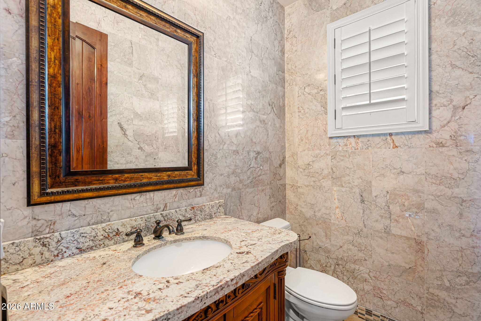 2822 East Constance Way Phoenix, AZ 85042 - Photo 39 of 64 a bathroom with a granite countertop toilet a sink and a mirror