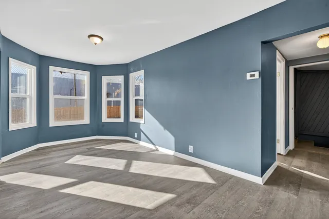 a view of an empty room with wooden floor and windows