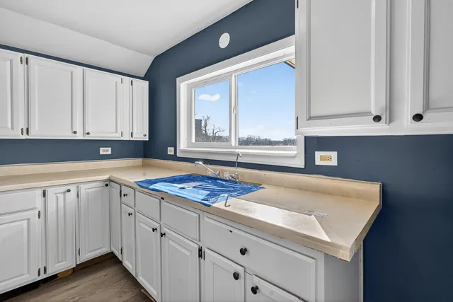 a kitchen with white cabinets and sink