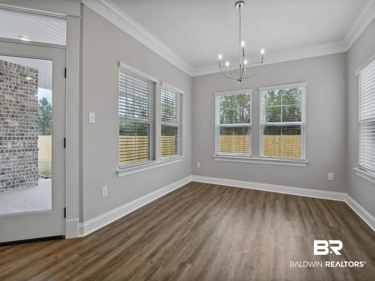 10174 Grady Lane Mobile, AL 36695 - Photo 6 of 14 Unfurnished dining area with crown molding, dark wood-style floors, and a chandelier