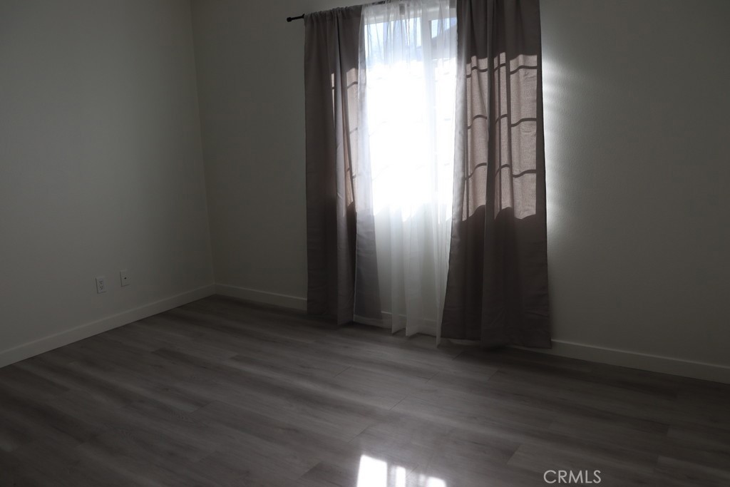 16731 Parthenia Street, Unit 3 Northridge, CA 91343 - Photo 28 of 37 an empty room with wooden floor and windows with curtains