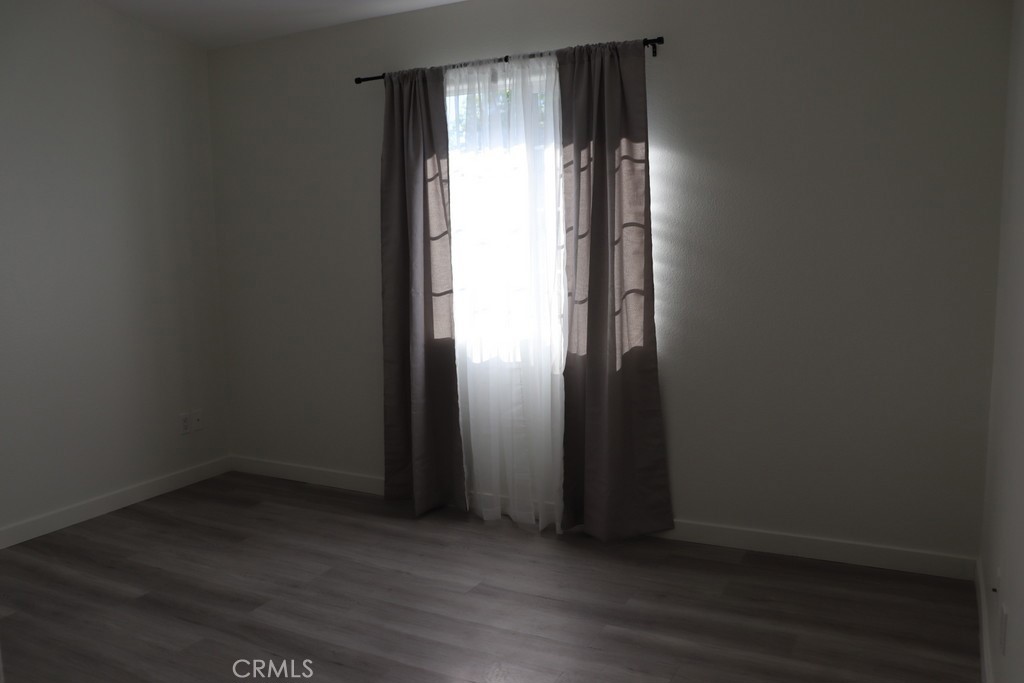 16731 Parthenia Street, Unit 3 Northridge, CA 91343 - Photo 30 of 37 an empty room with wooden floor and windows with curtains