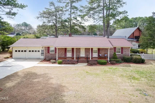a front view of a house with a garden and tree