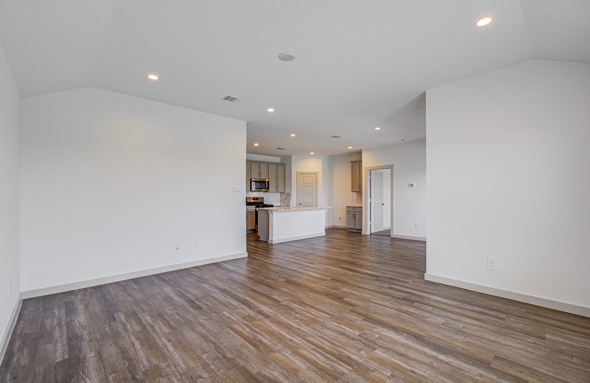 7903 Wrangler Shack Lane Rosharon, TX 77583 - Photo 21 of 29 This inviting, open-concept living space features elegant wood flooring and recessed lighting, seamlessly flowing into a sleek modern kitchen with pristine white cabinetry and high-end stainless steel appliances.