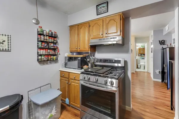 a kitchen with stainless steel appliances a stove a sink cabinets and wooden floor