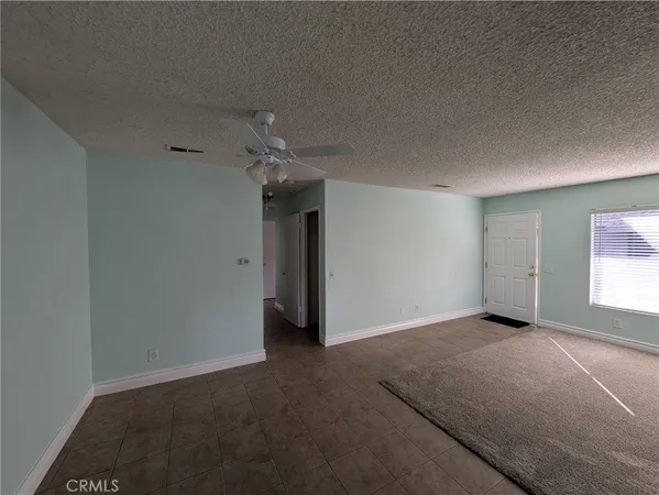 an empty room with windows and chandelier fan